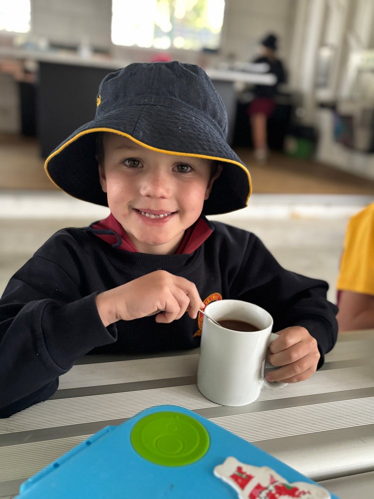 A student enjoying a hot chocolate prepared in Cooking Club.