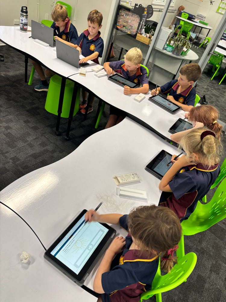 An image of students working on their laptops in the classroom.